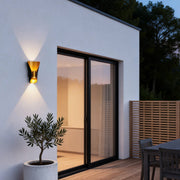Small up down wall lights illuminating a modern house entrance with warm directional glow.