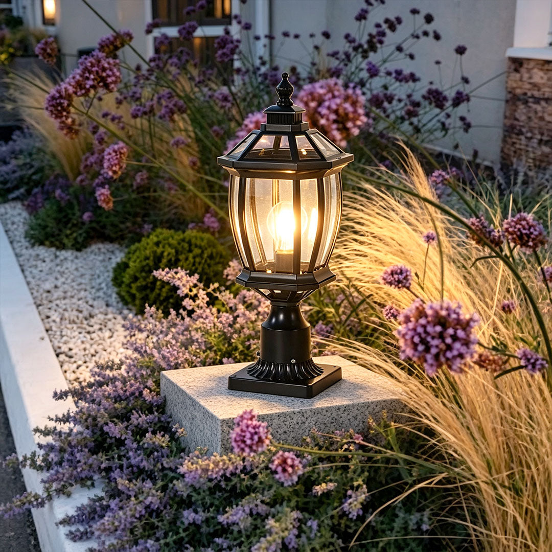 Solar column pillar light accenting a landscaped garden bed on a low stone pedestal.