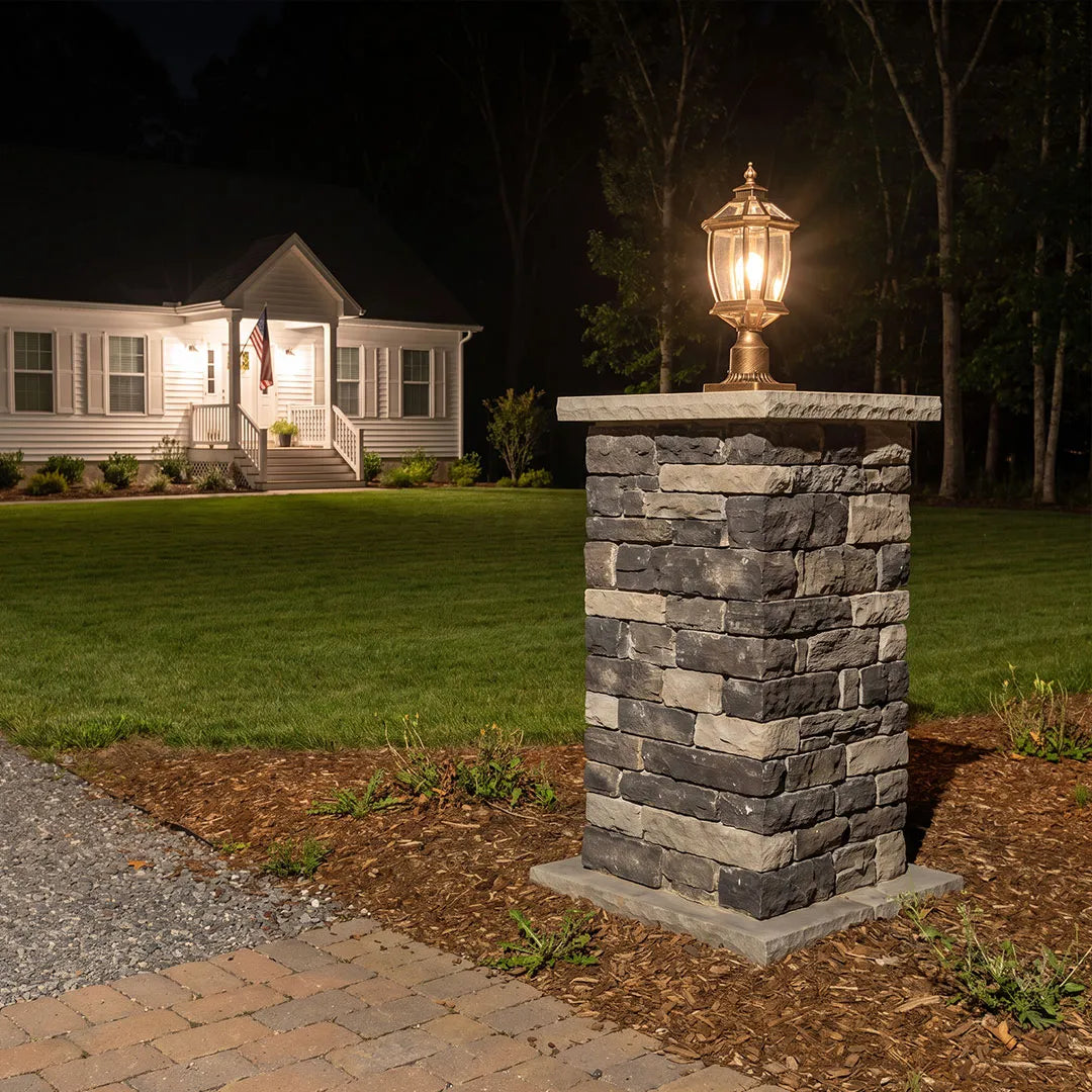 Solar column pillar light mounted on a stone post beside a driveway at night.