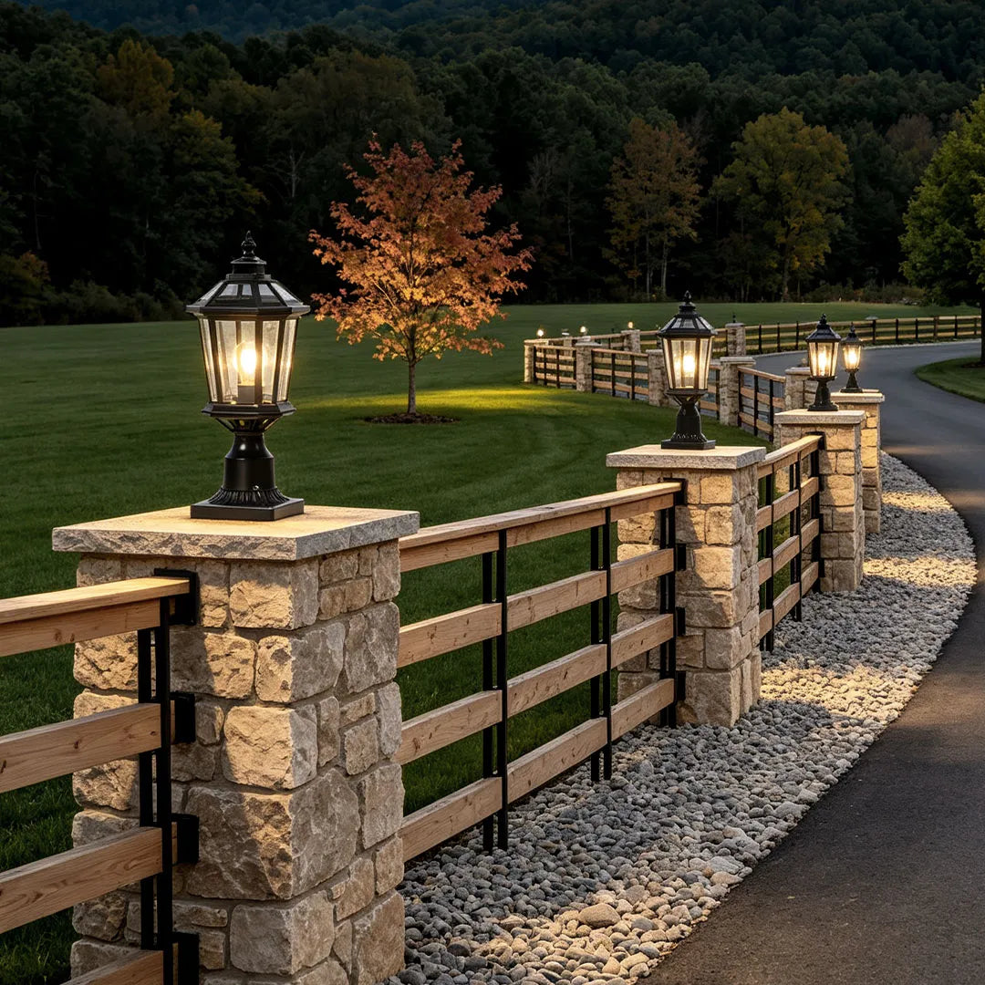 Solar column pillar lights lining multiple stone fence posts along a country driveway at dusk.