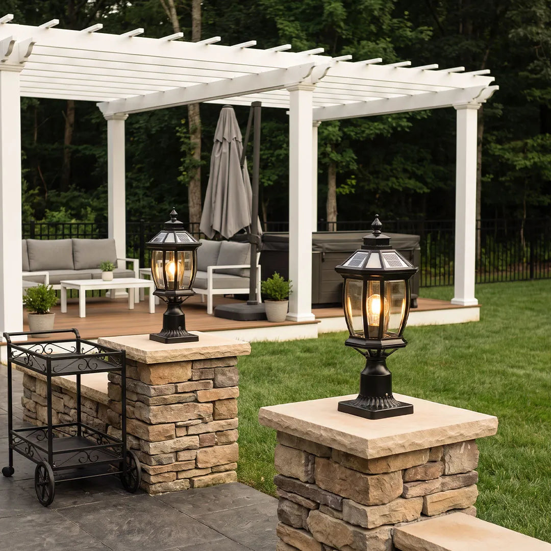 Solar column pillar lights installed on stone patio columns beside a white pergola.