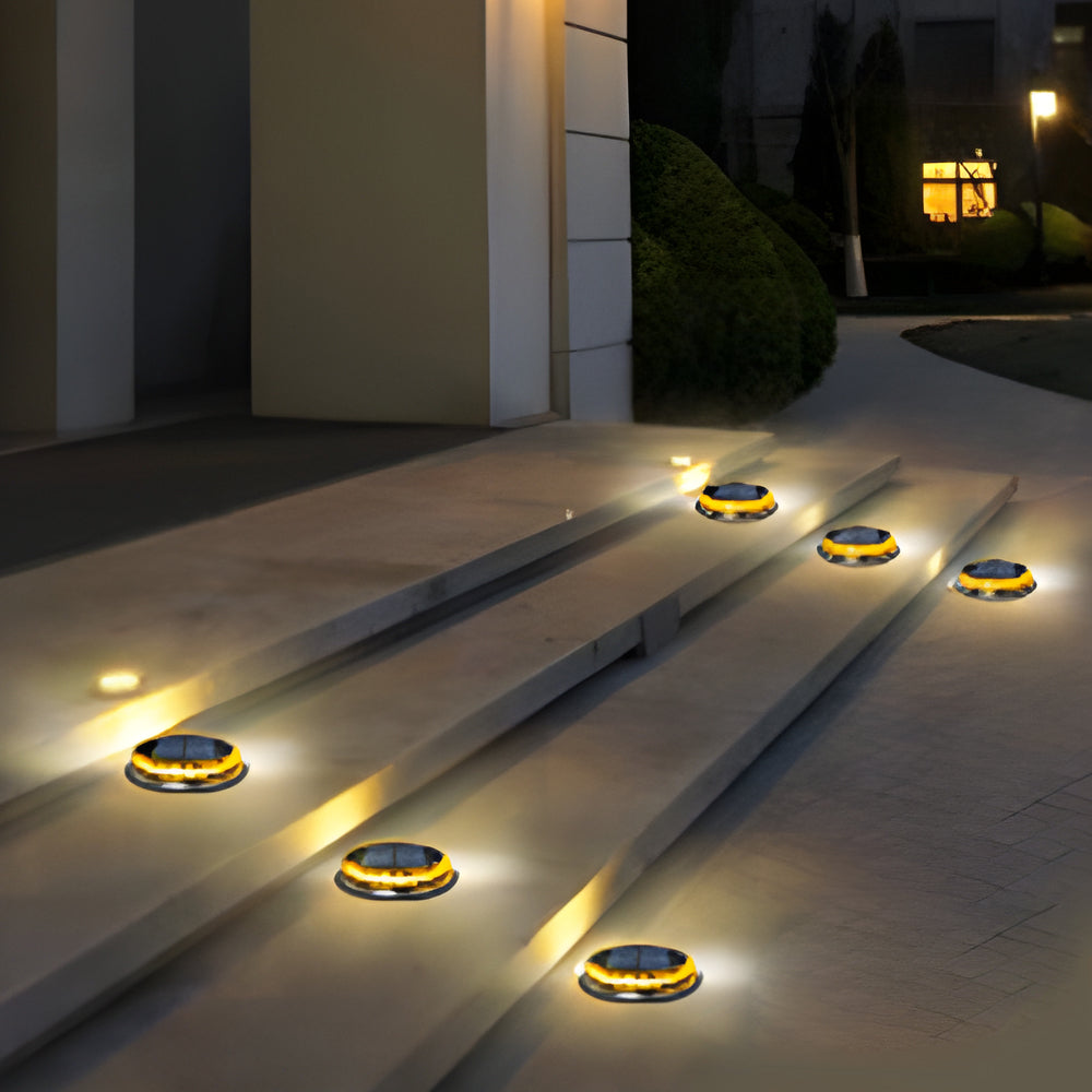 Solar disc light installed along concrete steps, providing soft illumination at night.