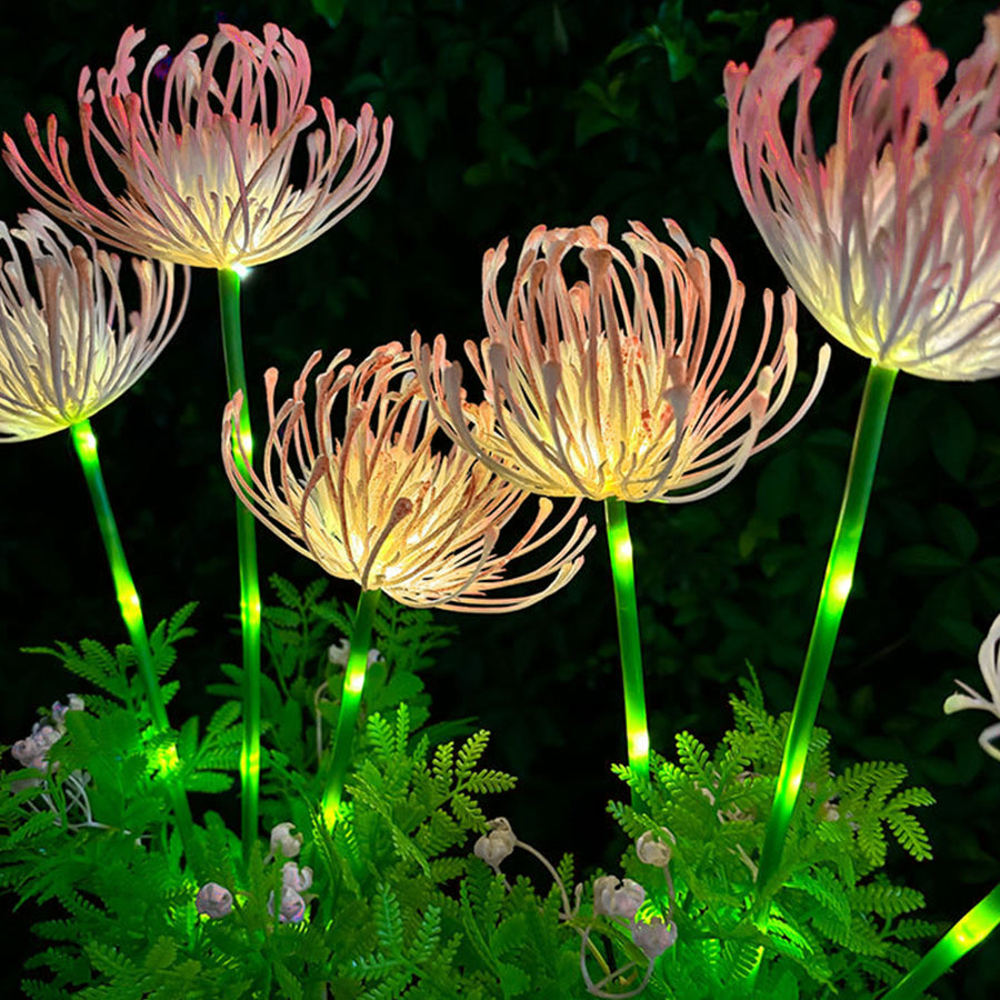 Decorative solar flower lights with pink blooms and green foliage creating enchanting garden illumination