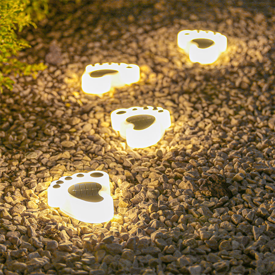 Solar-powered footprint pathway lights creating warm illumination along garden walkway at night