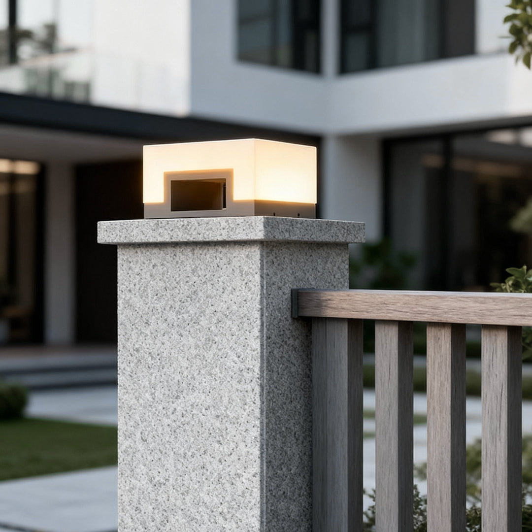 Modern solar front lawn light mounted on concrete fence pillar in residential yard.