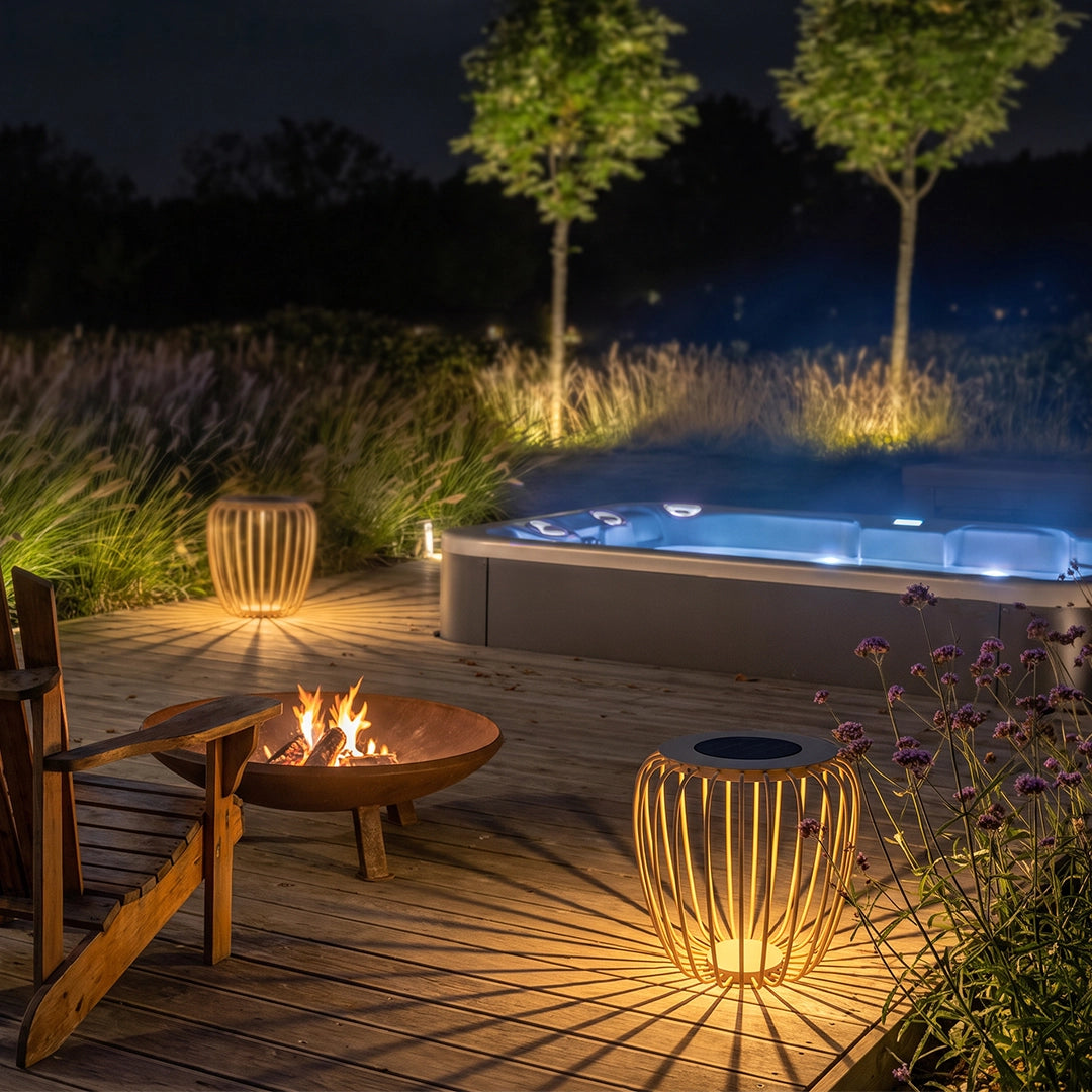Solar garden lanterns glowing beside a fire pit and hot tub in a landscaped backyard.