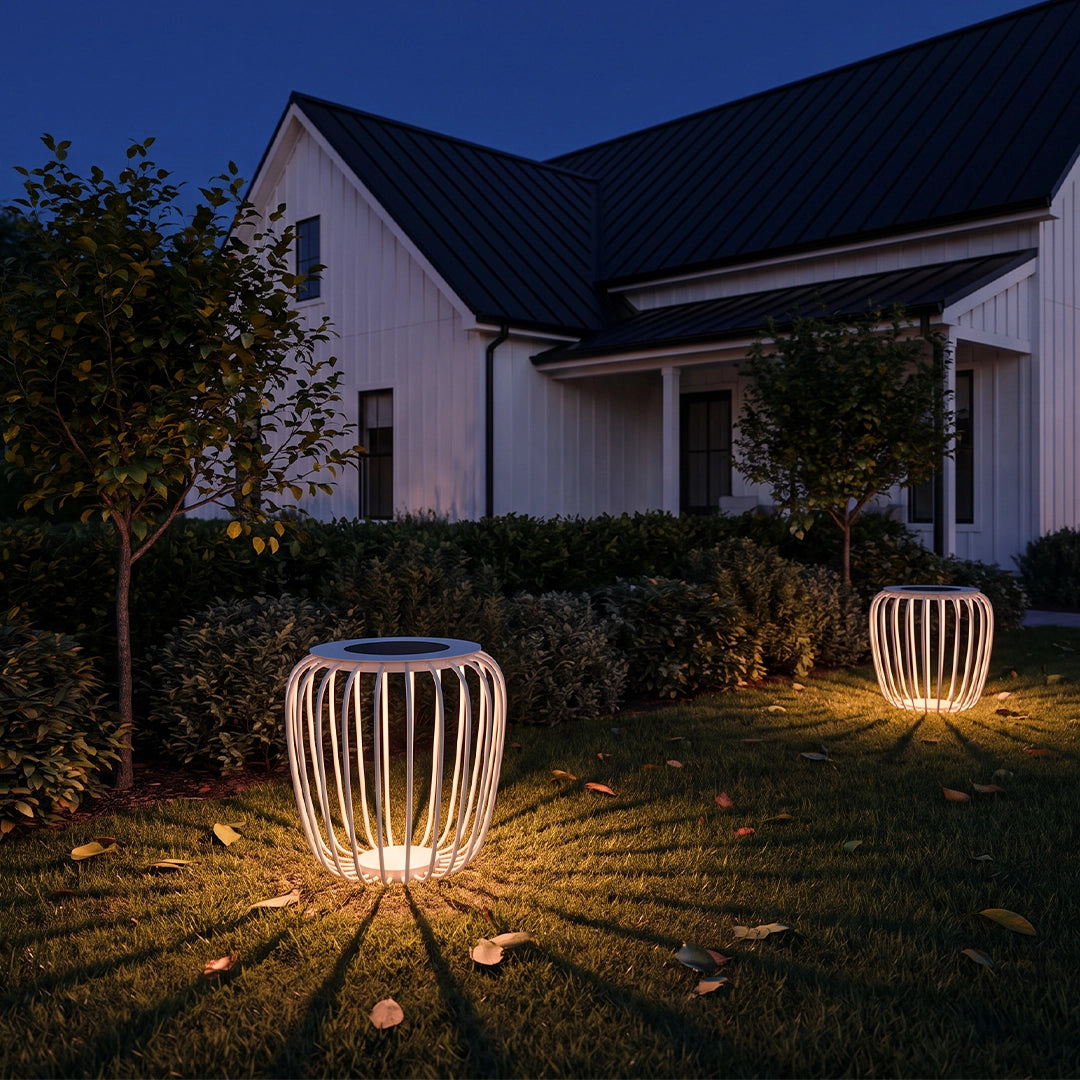 Solar garden lanterns illuminating a front yard lawn beside a modern house at dusk.