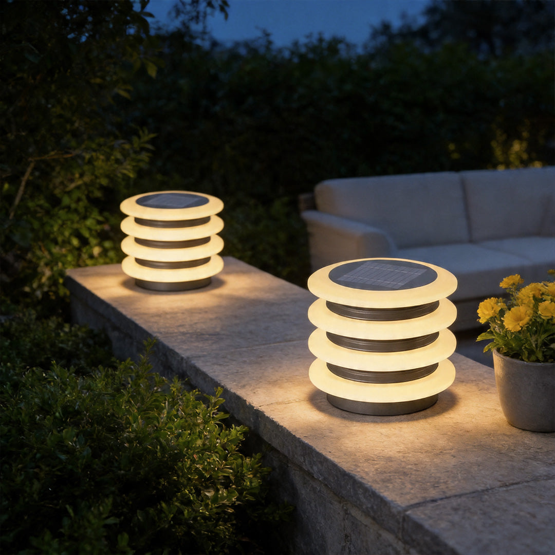 Solar garden pillar lights illuminating outdoor seating area with warm modern layered lighting design.
