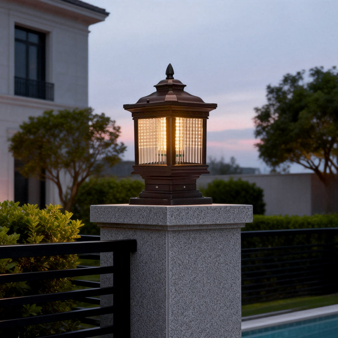 Solar garden post lights installed on a stone pillar, providing warm ambient lighting for an elegant outdoor driveway entrance.