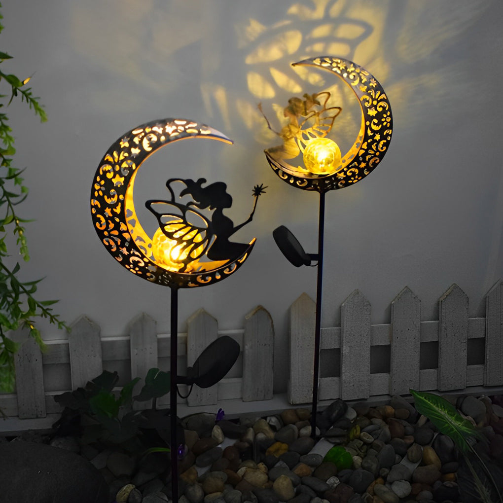 Decorative solar garden stake lights with crescent moon designs casting patterned shadows near a garden fence.