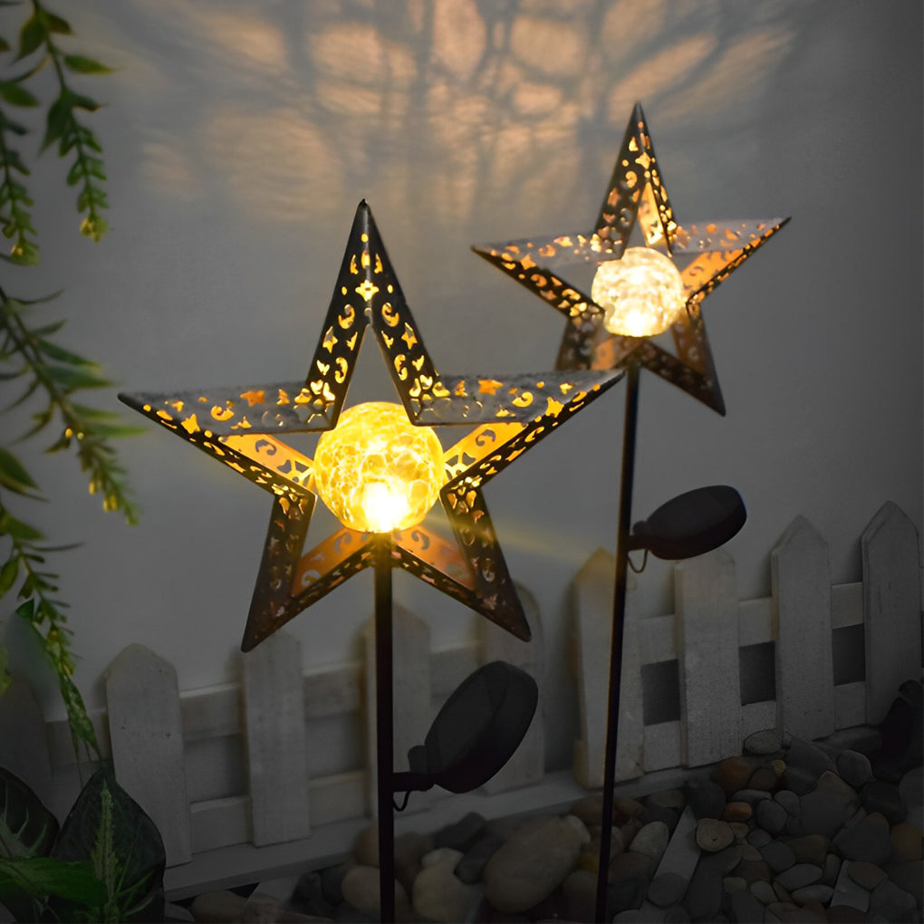 Solar garden stake lights with star-shaped shades creating warm patterned illumination beside a fence.