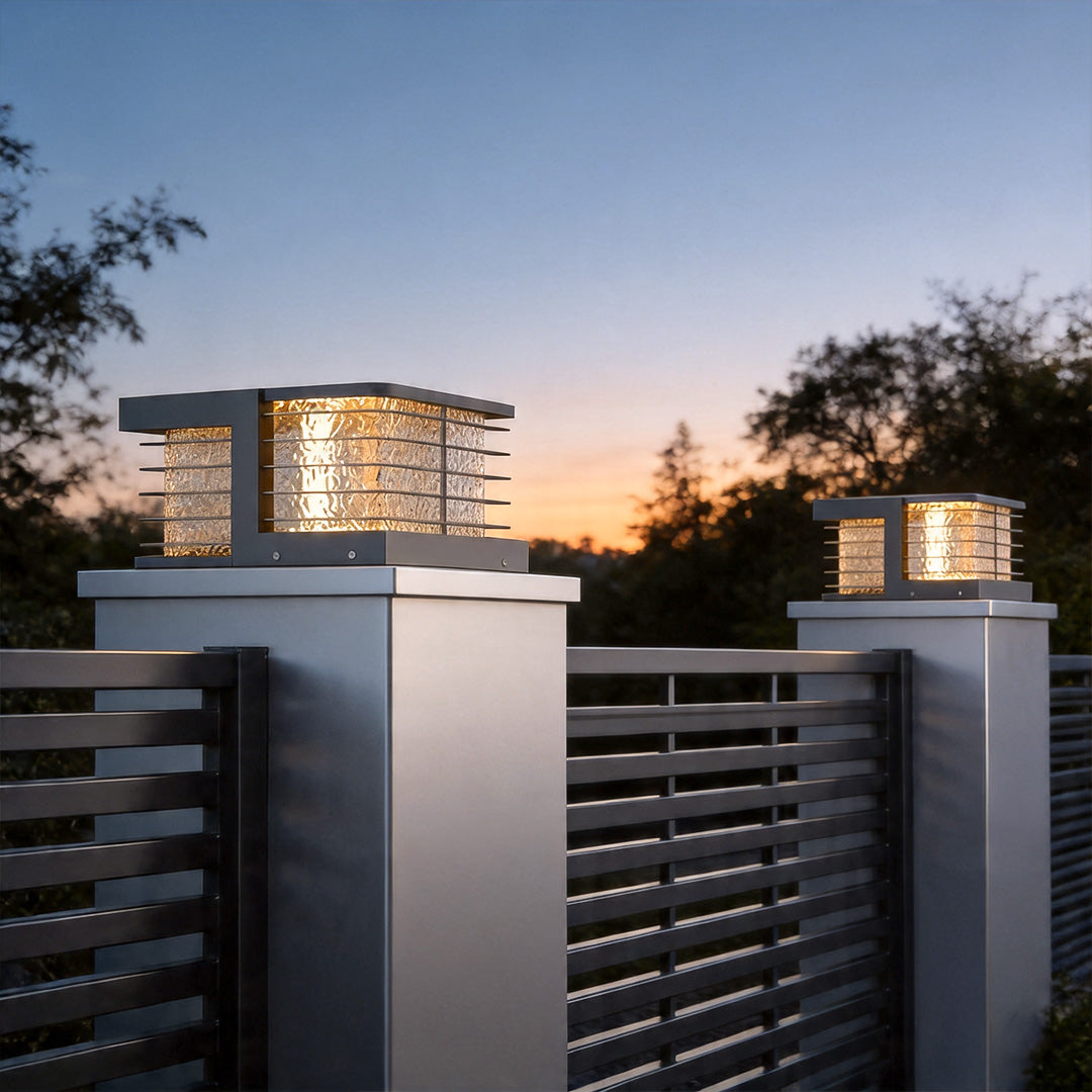 Solar gate pillar lights illuminating modern driveway fence with warm ambient evening glow.