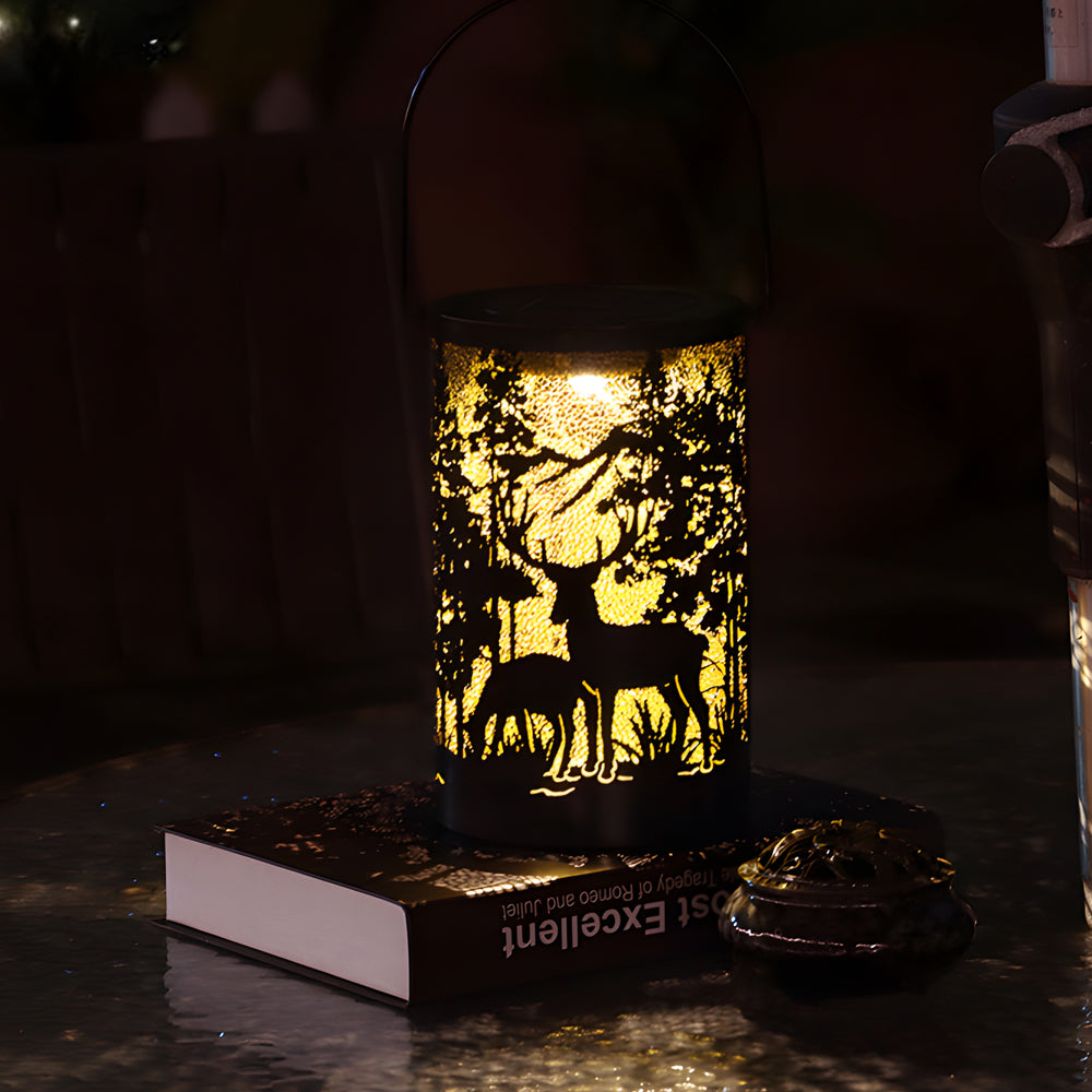 Solar hollow out lantern with deer and tree cut-outs, placed on a white surface.
