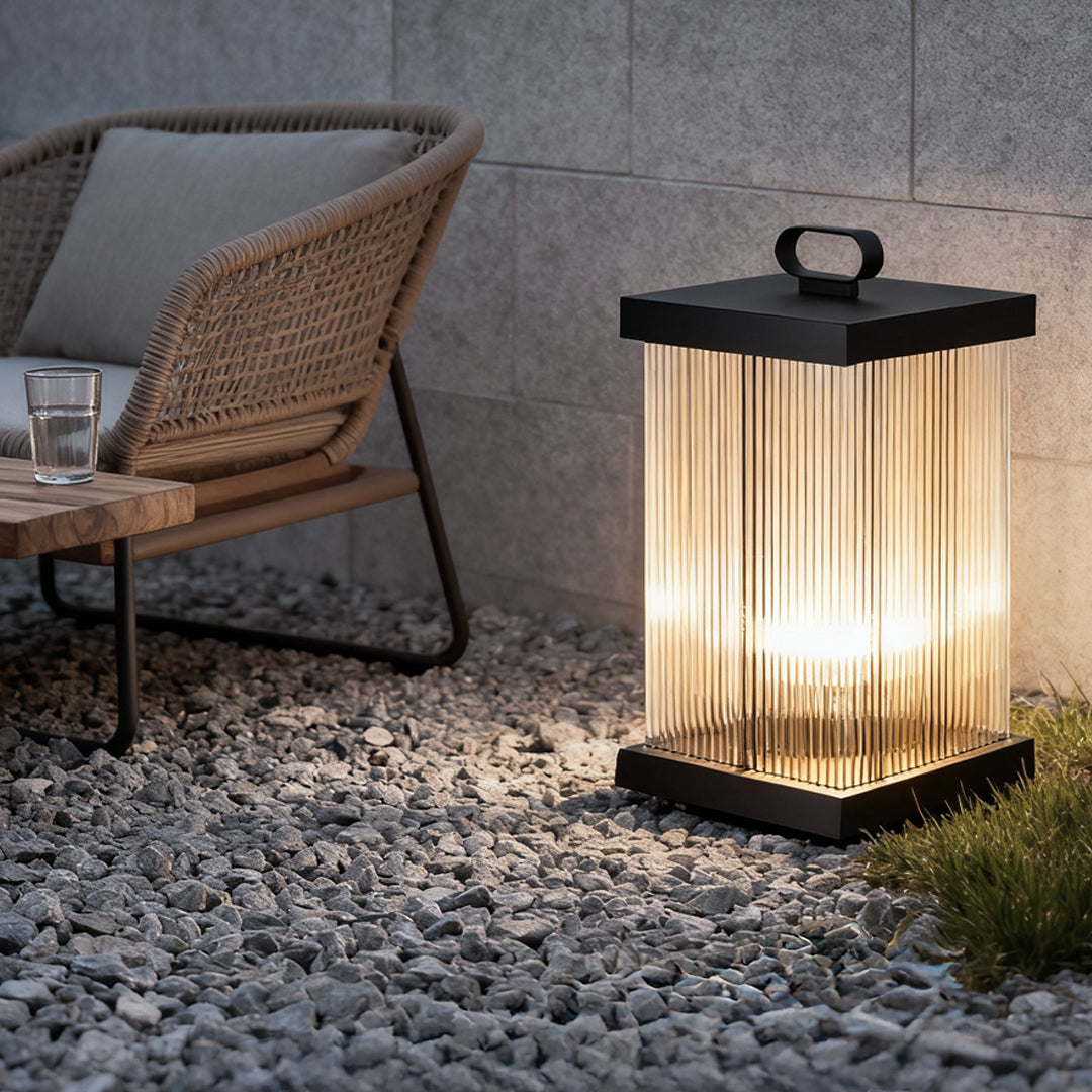 Contemporary solar lantern lighting a gravel patio next to outdoor chair.