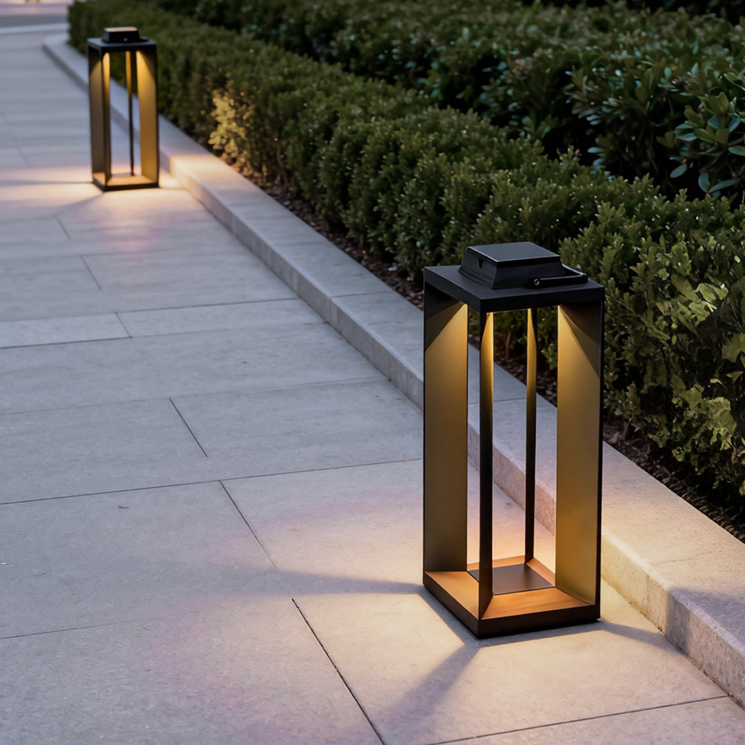Portable solar lantern placed along an outdoor garden walkway, providing warm ambient lighting at night.