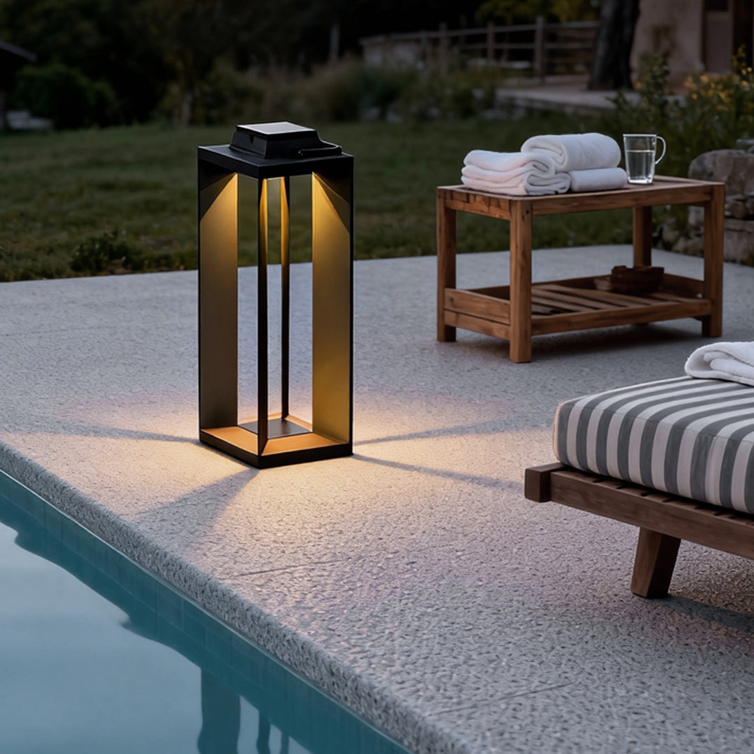 Solar powered portable lantern positioned beside a poolside lounge area for evening lighting.