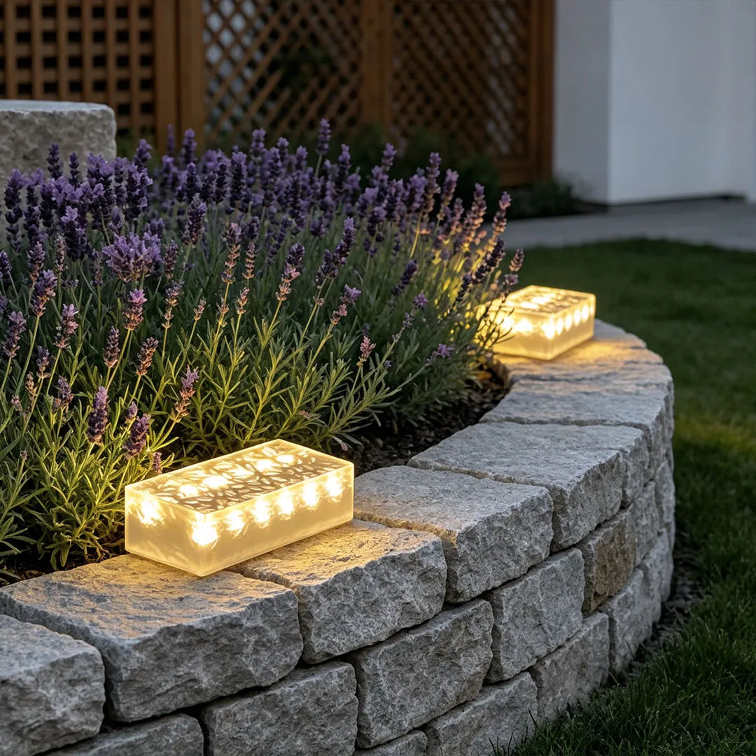 Solar LED step lights resting on a curved stone garden wall beside blooming lavender.