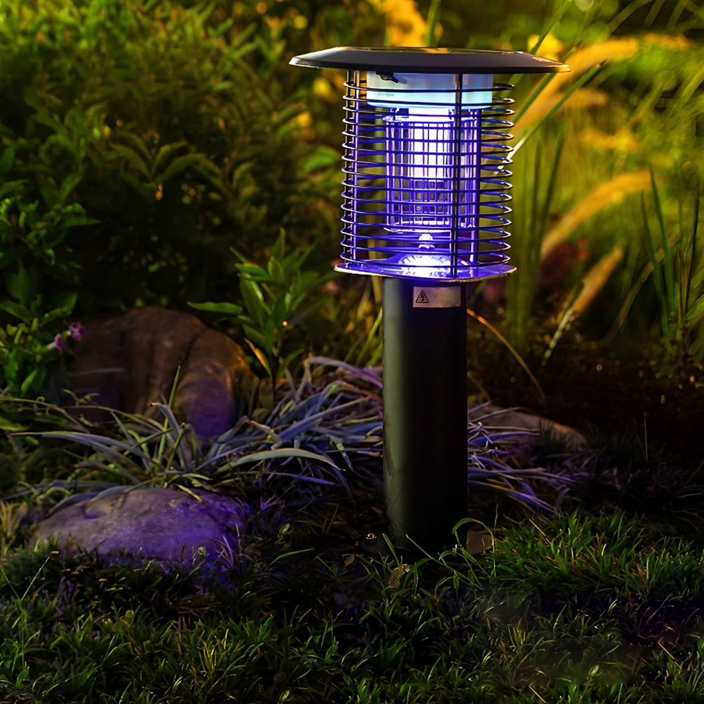 Solar light bug zapper installed in garden at night, emitting blue UV light to attract and kill insects.