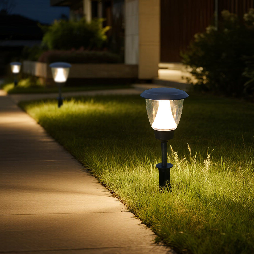 Solar garden light illuminating green grass area with warm LED glow during evening hours