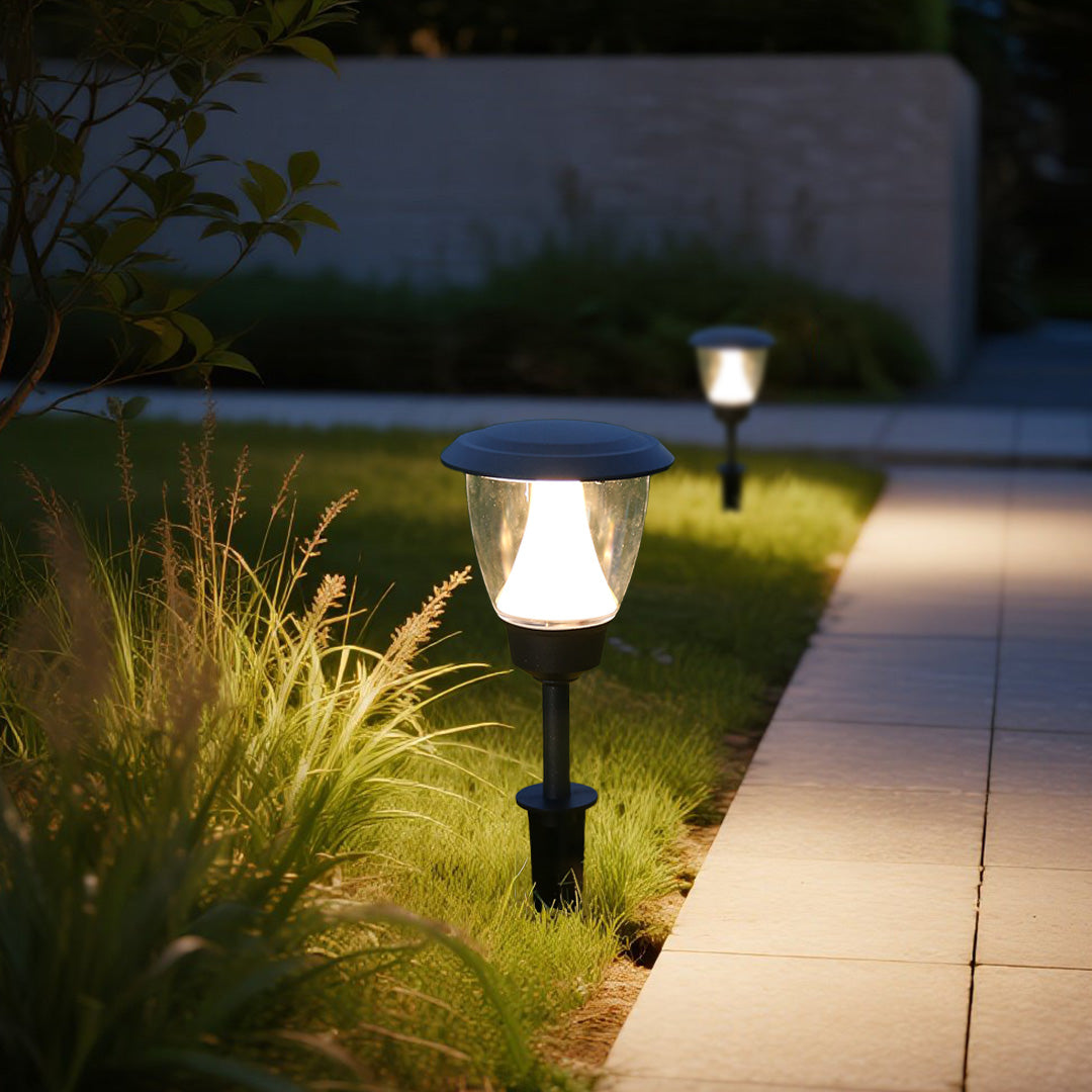 Solar garden light illuminating green grass area with warm LED glow during evening hours