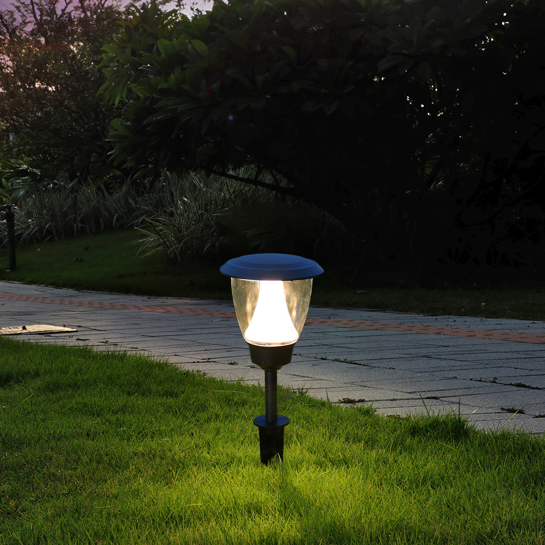 Solar garden light illuminating green grass area with warm LED glow during evening hours
