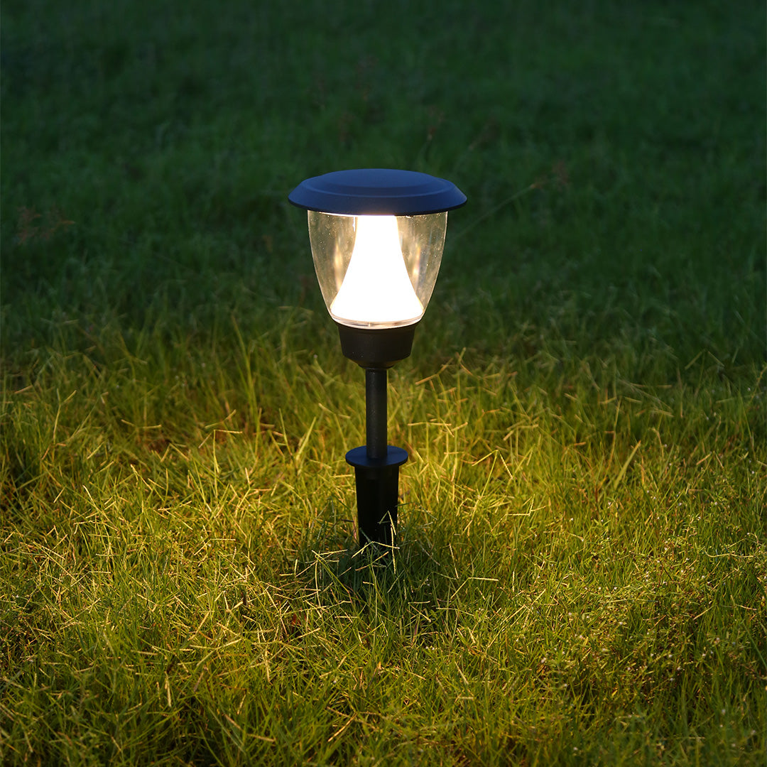 Solar garden light illuminating green grass area with warm LED glow during evening hours