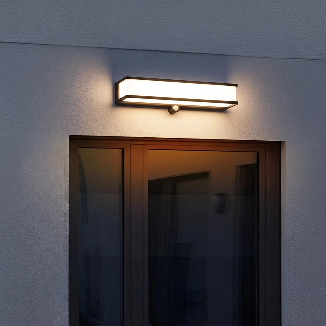 Solar light outdoor wall mount installed above double doors on a modern exterior wall at dusk.