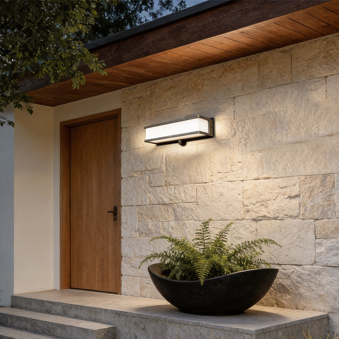 Solar light outdoor wall mount with a modern rectangular design, illuminating a stone wall entrance.