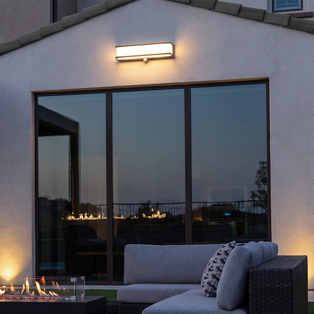 Solar light outdoor wall mount above large patio doors on a modern home exterior at dusk.