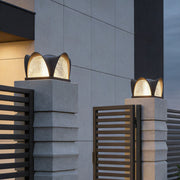 Solar light pillar with a modern design, illuminating a driveway entrance at night.