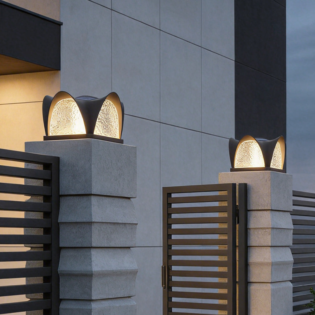 Solar light pillar with a modern design, illuminating a driveway entrance at night.