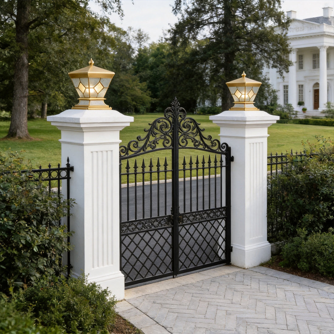 Solar lights outdoor gate pillar mounted on white columns beside elegant wrought iron gates.
