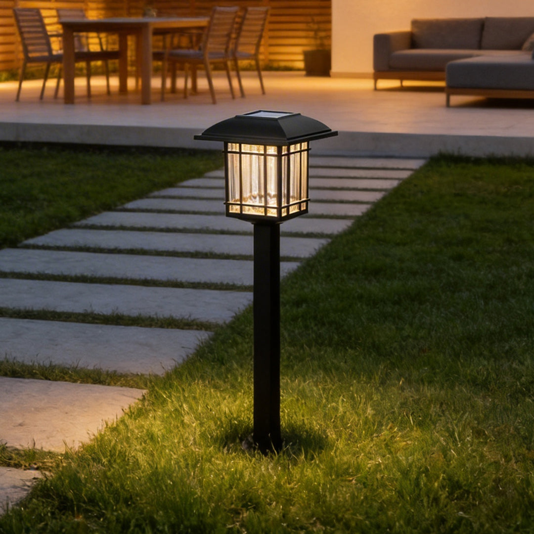 Black solar path lights casting warm light along a garden walkway