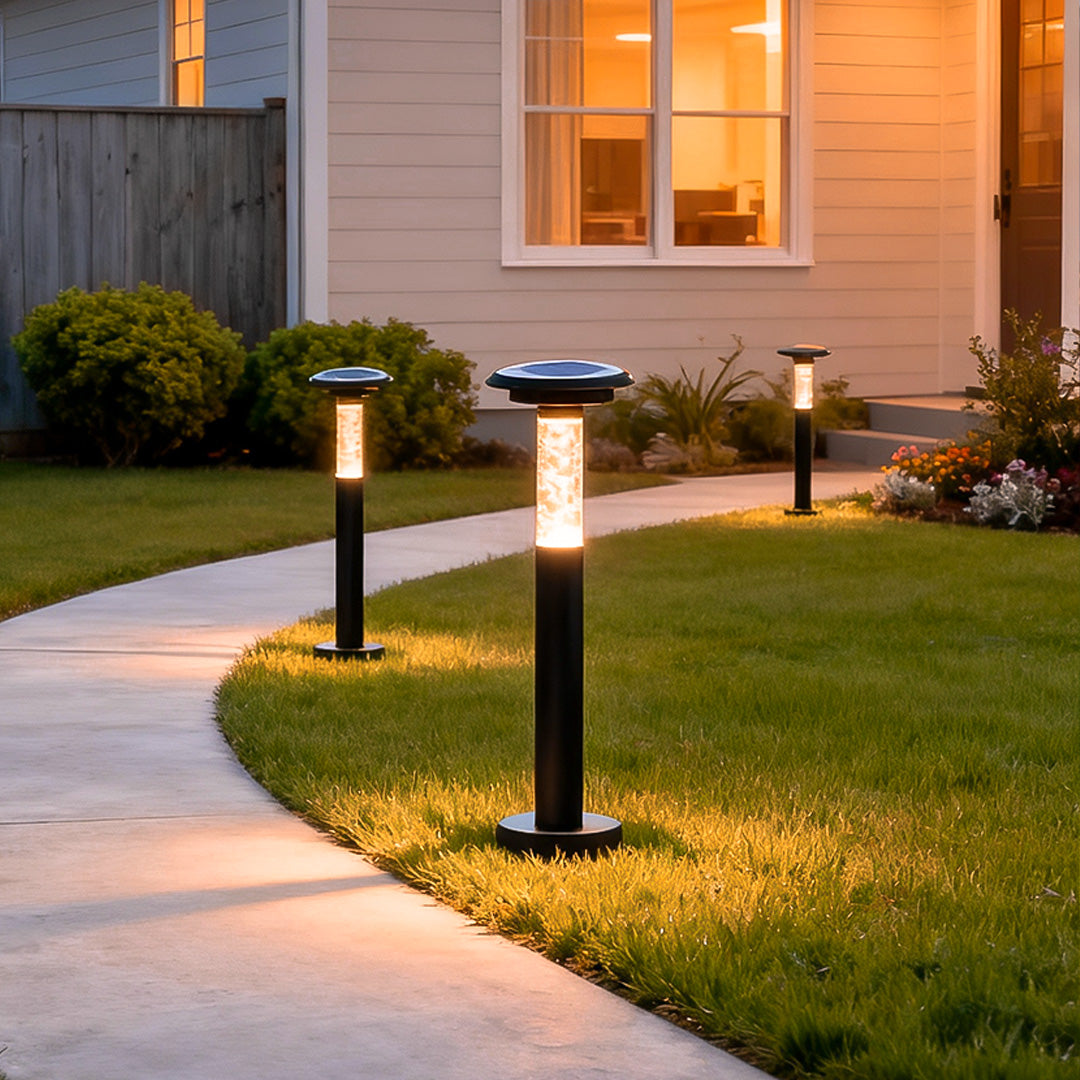 Warm solar outdoor path lighting illuminating a curved garden walkway beside a modern home during dusk.