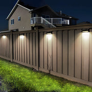 Solar outdoor wall lights dusk to dawn installed along a wooden fence, providing security and pathway illumination.