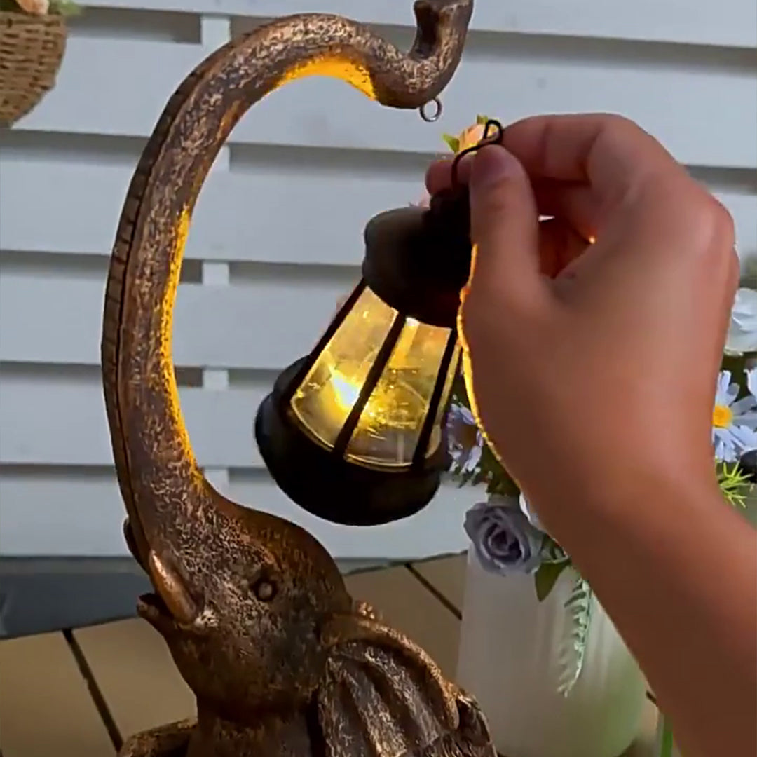 Hand installing or adjusting solar panel component on top of elephant garden lantern fixture