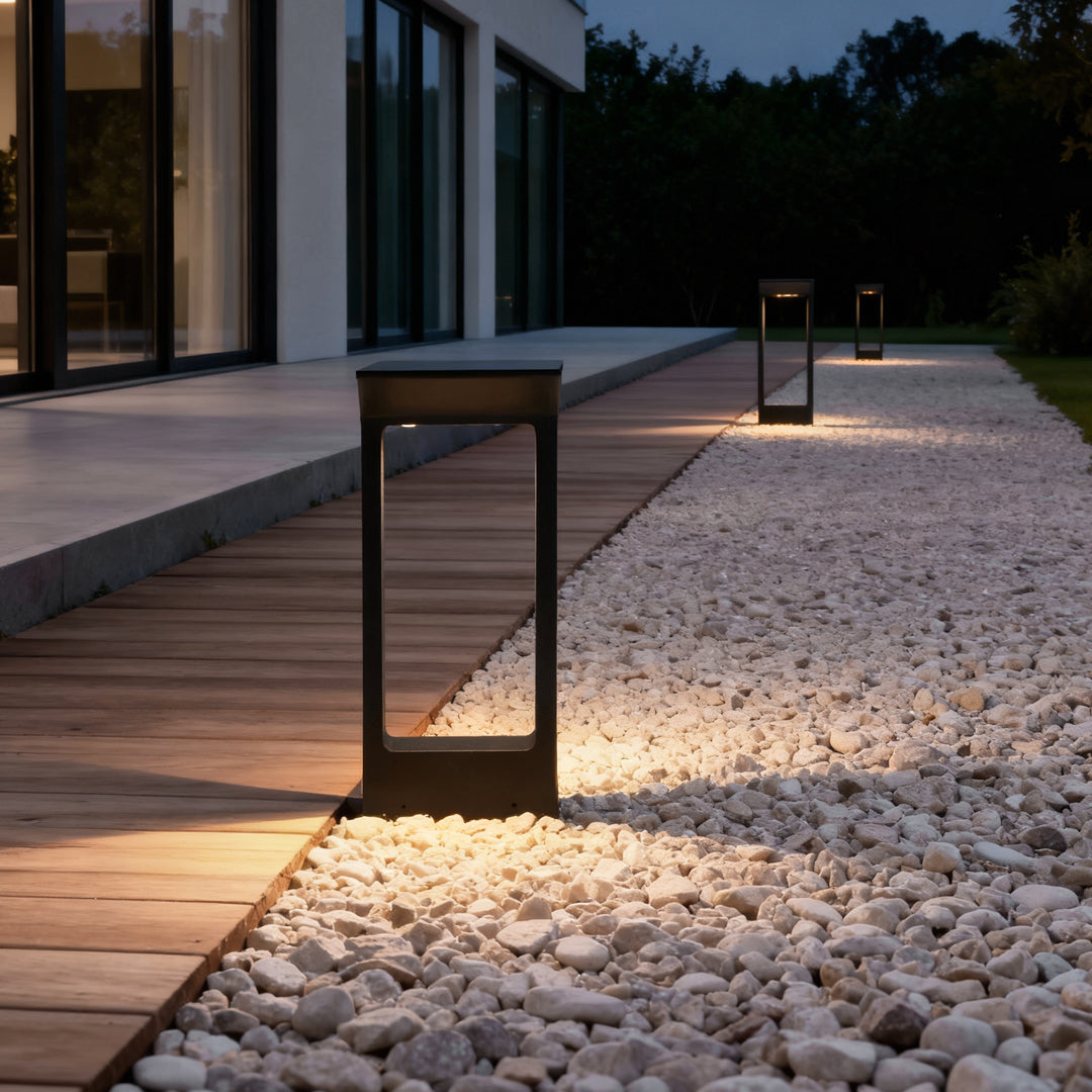 Black solar pathway outdoor lamp placed beside gravel path and wooden deck.