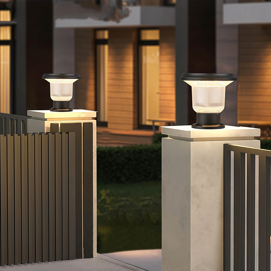 Solar-powered pillar light on a pillar in the garden, casting soft light on surrounding flowers.