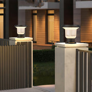 Solar-powered pillar light on a pillar in the garden, casting soft light on surrounding flowers.