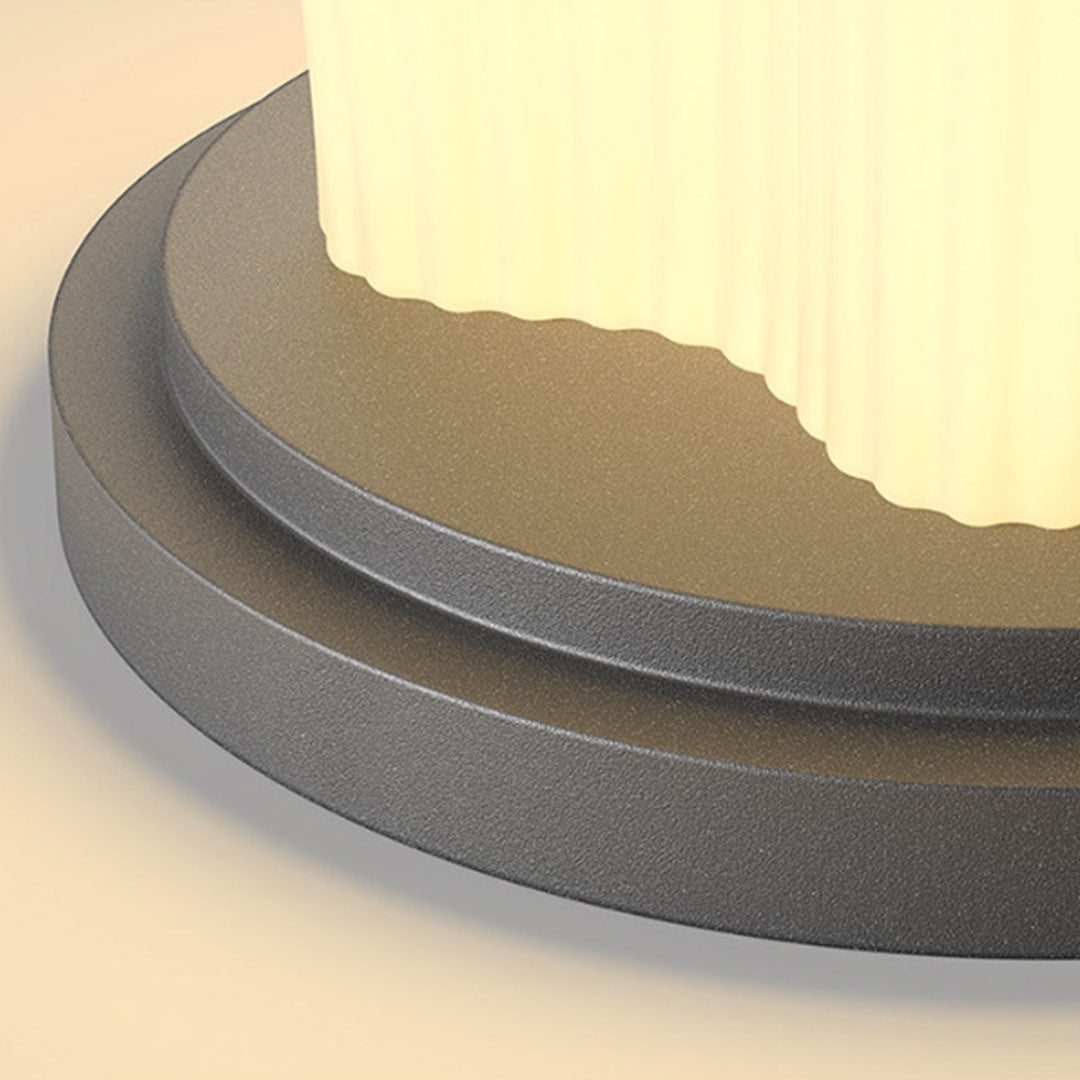 Close-up detail of solar pillar light showing textured metal base and illuminated diffuser surface.
