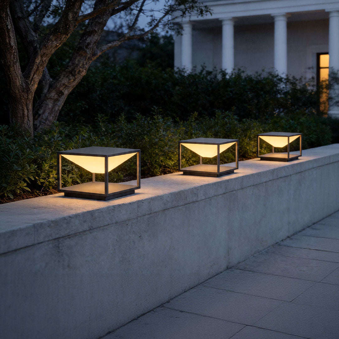 Solar pillar light outdoor arranged along concrete wall with stylish ambient evening illumination.