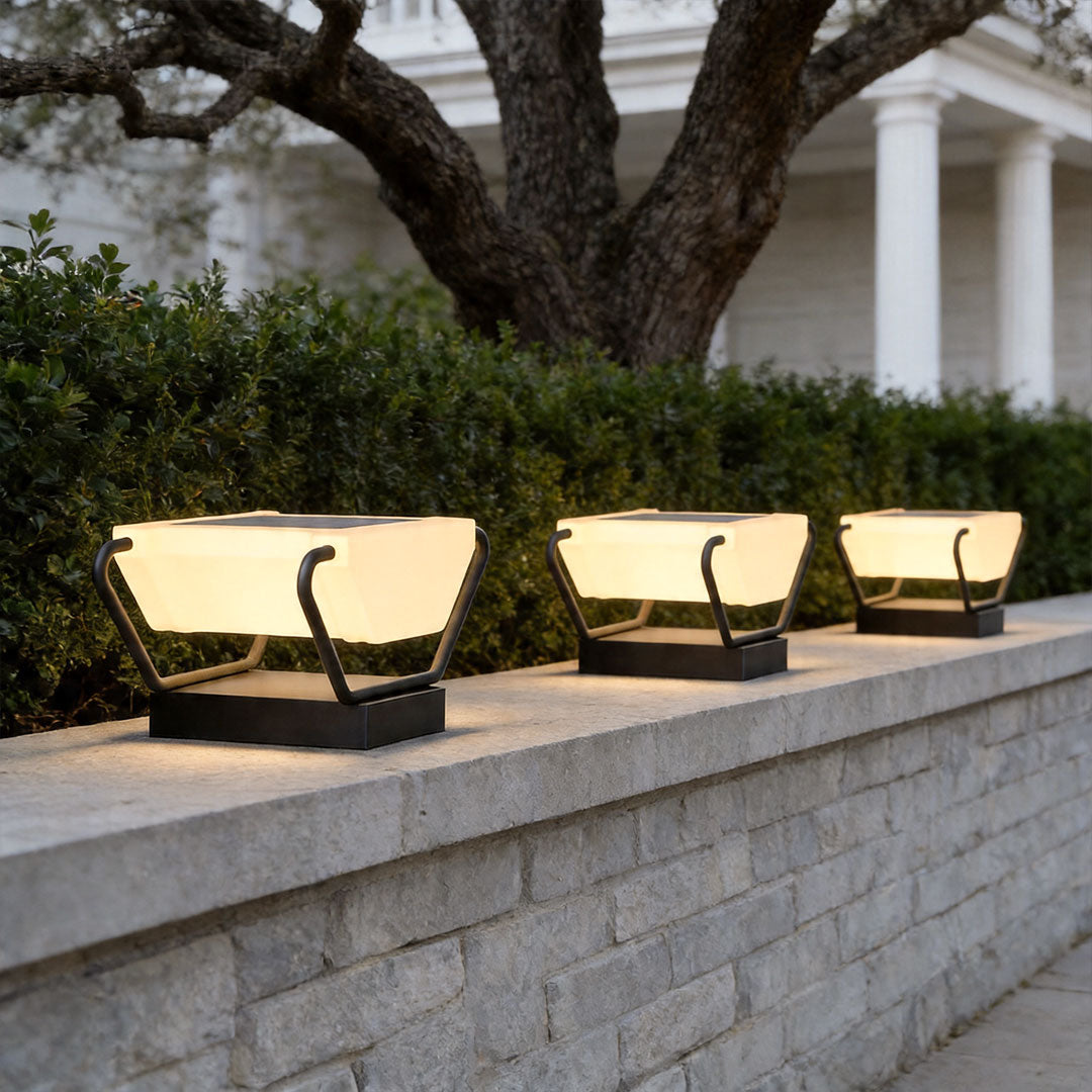 Solar pillar lighting arranged along concrete wall with stylish modern landscape lighting design.