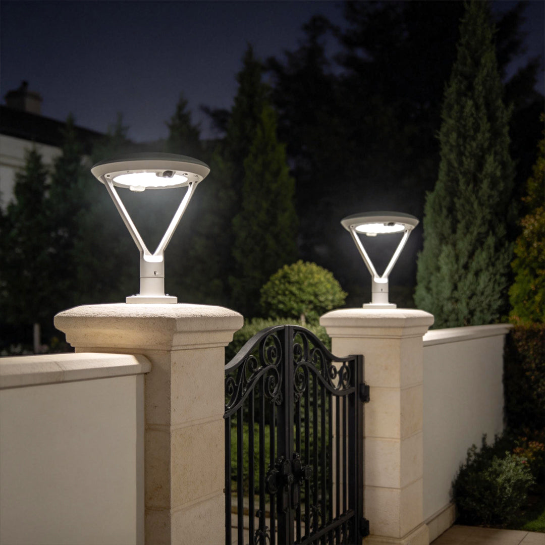 Solar pillar lights with a modern design, illuminating a garden fence at night.