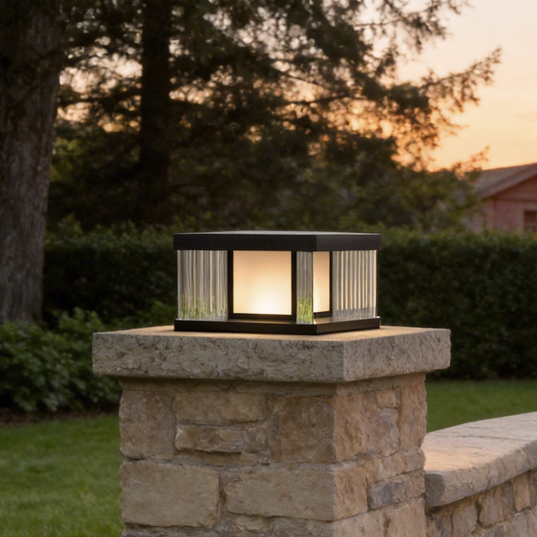 Solar pillar lights with a modern design, illuminating a stone pillar in a garden.