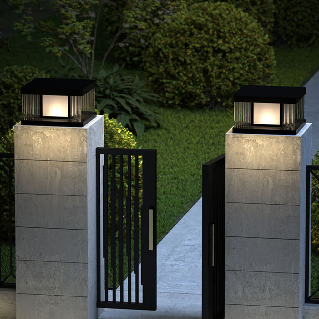 Solar pillar lights with a sleek black frame, providing warm light along a pathway.