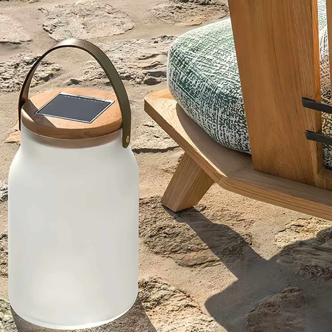 Portable solar powered camp lantern placed on sandy beach area, ideal for camping and outdoor adventures.