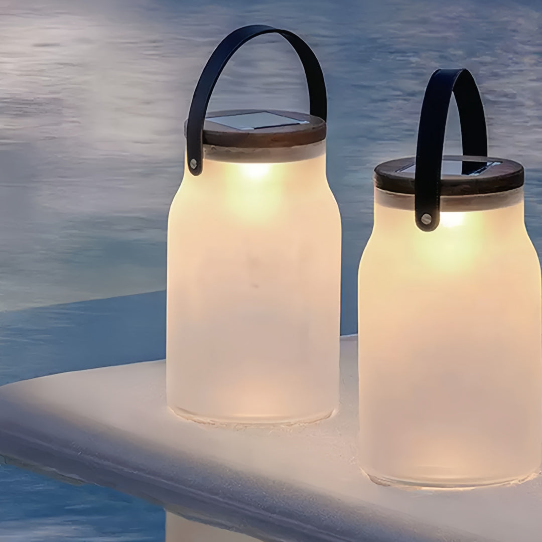 Two glowing solar powered camp lanterns illuminating a lakeside evening environment.