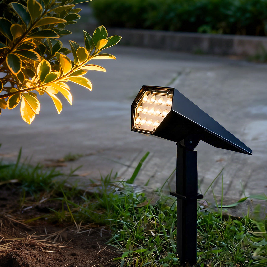 Solar-powered flood spike light illuminating garden plants with warm white glow for outdoor landscape lighting.