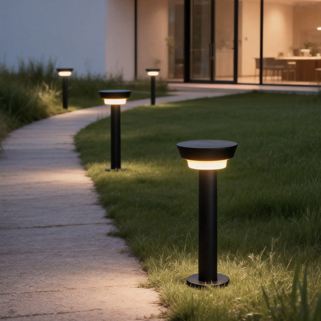 Solar powered garden path lights illuminating a curved outdoor walkway beside a modern lawn and landscape at dusk.