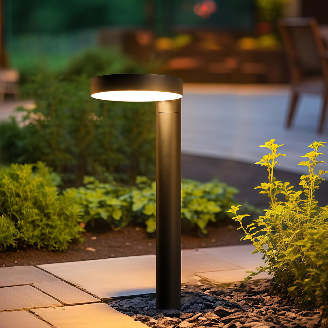 Solar-powered LED light standing by garden stairs, providing soft illumination.